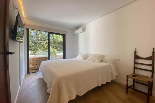 ein weißes Schlafzimmer mit einem Bett und einem Fenster in der Unterkunft Beautiful designer home in Illetas in Illetas