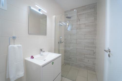 a white bathroom with a sink and a shower at Fernandes House in Machico