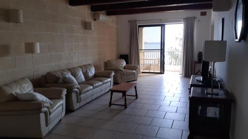 ビルゼブジャにあるSerena Flats, Serena Flat No 3, Triq Il-Fossilli Birzebbugiaのソファ付きのリビングルームが備わり、海の景色を望めます。