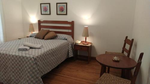 ein Schlafzimmer mit einem Bett, einem Tisch und einem Stuhl in der Unterkunft Playa Grande in Piriápolis