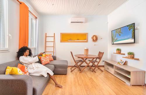 a woman sitting on a couch in a living room at Foyal Suites in Fort-de-France