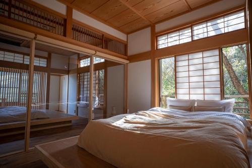 a bedroom with a large bed in a room with windows at プライベートリゾート 月灯 in Atami