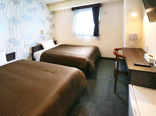 a hotel room with two beds and a desk at Hotel Trend JR Uji Ekimae in Uji