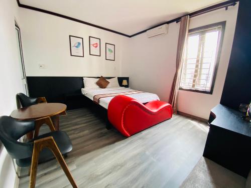 Habitación con cama con silla roja y mesa. en Khách sạn Hoàng Gia, en Thái Bình