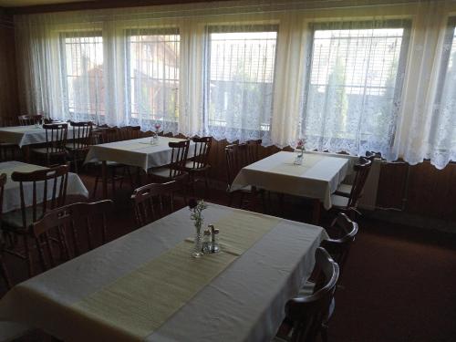 a dining room with tables and chairs and windows at Penzión Zátoka in Liptovský Mikuláš