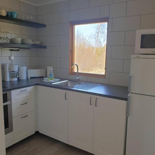 a kitchen with white cabinets and a sink and a window at Eckerö Camping & Stugor in Eckerö
