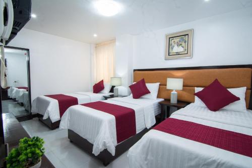 a hotel room with two beds with red and white sheets at Diamond Hotel And Resto in Catarman