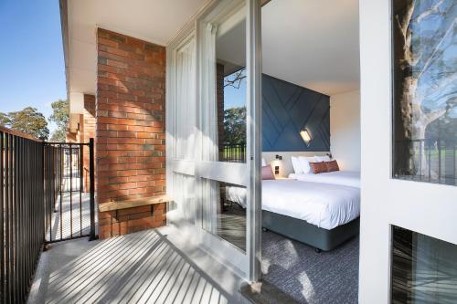 a bedroom with a bed and a balcony at Nightcap at Sandown Park Hotel in Noble Park