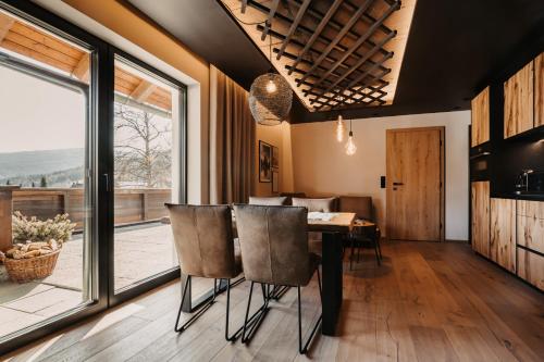 a dining room with a table and chairs and a large window at Hoamat House I Boutique Apartments in Sankt Margarethen im Lungau