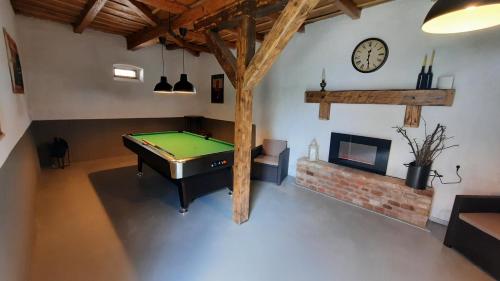 a room with a pool table and a clock on the wall at Tornácos Vendégház in Hajdúnánás