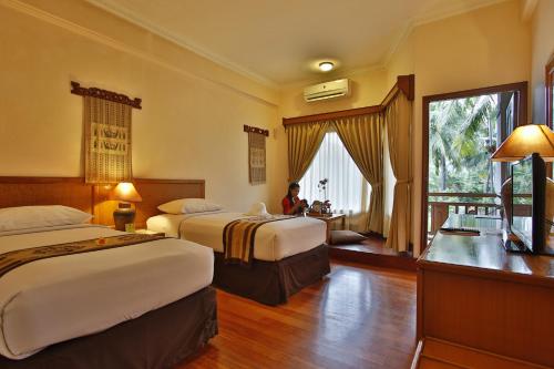 a hotel room with two beds and a woman sitting in the window at Jayakarta Hotel Lombok in Senggigi 