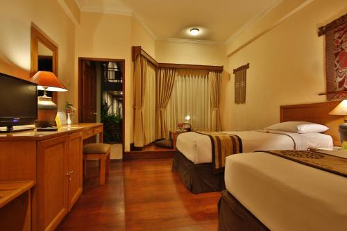 a hotel room with two beds and a television at Jayakarta Hotel Lombok in Senggigi 