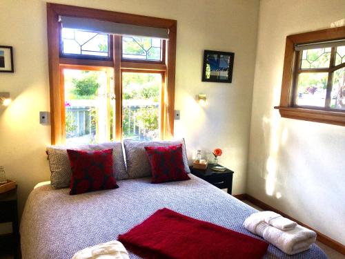a bedroom with a bed with red pillows and a window at Riverside B & B in Kurow