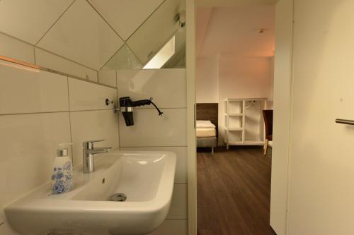 a white sink in a bathroom with a bedroom at Hotel Weinert in Neubrandenburg