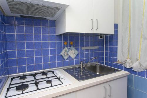 uma cozinha em azulejos azuis com um fogão e um lavatório em M116 - Marcelli, bilocale in centro e fronte mare em Marcelli