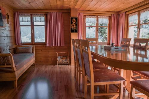 a dining room with a table and a bed and windows at Ferienhof Metzler in Schwarzenberg im Bregenzerwald