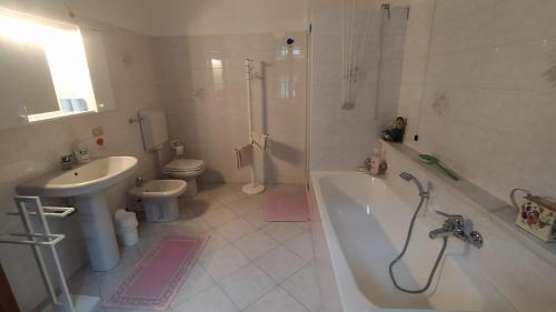a bathroom with a tub and a toilet and a sink at Casa Almut & More - Lake Como Center - Varenna in Perledo