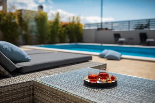 two glasses of wine on a table next to a pool at Belvedere Holidays Villas in Novigrad Istria