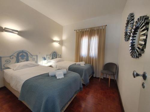 a hotel room with two beds and a chair at Be Happy Senhora da Rocha in Porches