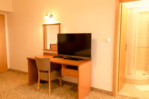 a room with a desk with a television and a mirror at Hotel VÍTKOVA HORA in Karlovy Vary