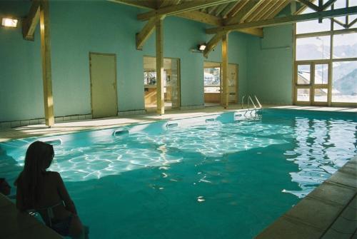 une femme assise à l'eau dans une piscine dans l'établissement appartement au pied des pistes, à La Chal