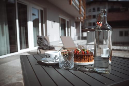 einen Tisch mit einer Flasche, einem Kuchen und einer Tasse in der Unterkunft Mountainview Apartments in Westendorf