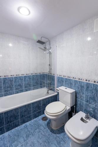 a blue and white bathroom with a toilet and a tub at Hotel Rural El Caserón in Soto de Cangas
