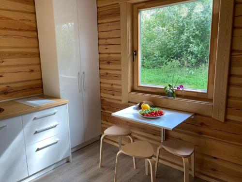 a kitchen with a table and two stools and a window at Zarasaičio ežero sodyba in Magučiai