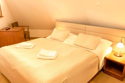 a bedroom with a white bed with two towels on it at Hotel VÍTKOVA HORA in Karlovy Vary