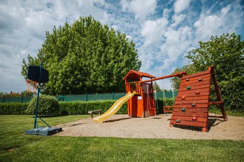 a playground with a slide and a basketball hoop at Németh Apartmanházak in Mórahalom