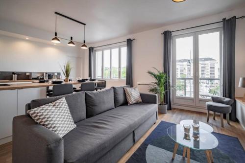 Il comprend un salon avec un canapé gris et une cuisine. dans l'établissement APPT VUE SUR LE PORT DE CAEN/ CENTRE VILLE PREMIUM, à Caen