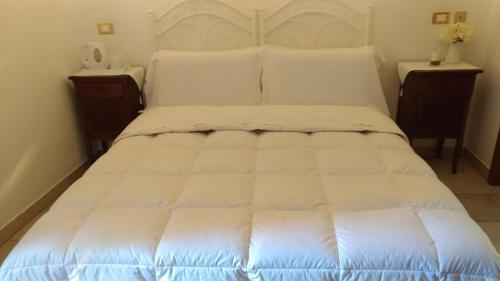 a large white bed in a room with two tables at B&B DIMORA PALMIERI in Monopoli