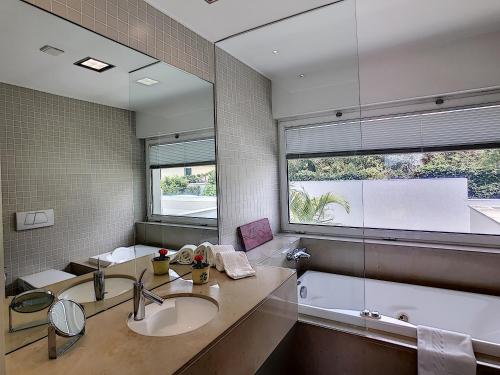 een badkamer met twee wastafels en een bad en een raam bij The White House - By LovelyStay in Funchal