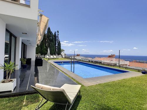 a house with a swimming pool with a chair and the ocean at The White House - By LovelyStay in Funchal