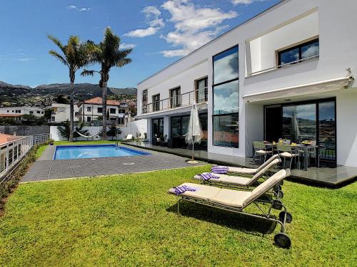 a house with a pool and two lounge chairs in the yard at The White House - By LovelyStay in Funchal
