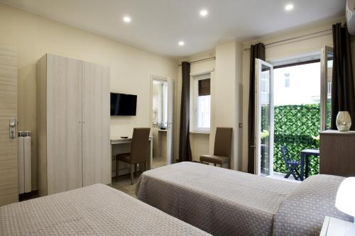 Pokój hotelowy z 2 łóżkami, biurkiem i oknem w obiekcie Six Rooms w mieście Neapol