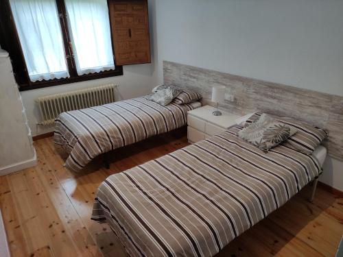 two beds in a room with wooden floors at El Campillo in Pelabravo
