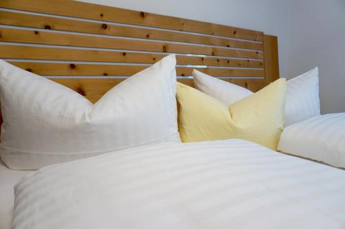 a white bed with white pillows and a wooden headboard at Ferienwohnung Paulo in Pfunds