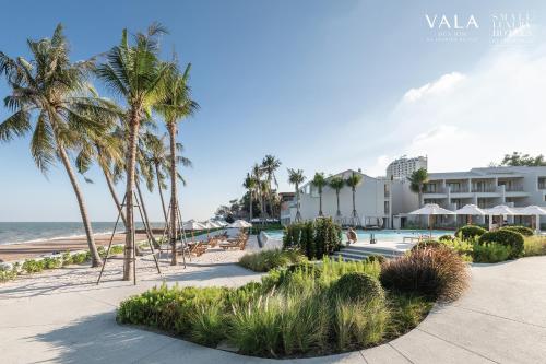a resort with a pool and palm trees and the ocean at VALA Hua Hin - Nu Chapter Hotels in Cha Am