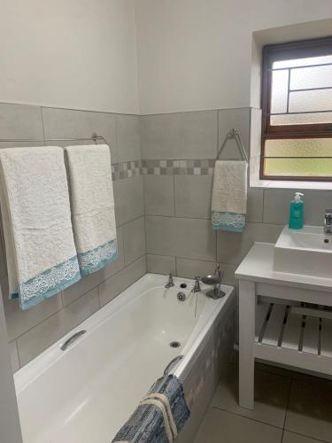 a bathroom with a bath tub and a sink at Cosy stone cottage in Stilbaai