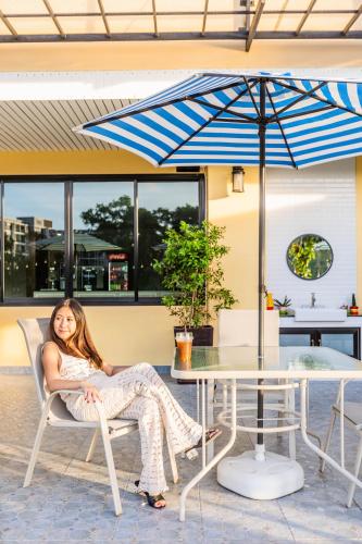 a woman sitting in a chair under an umbrella at USABAI Riverside Boutique Hotel in Chanthaburi