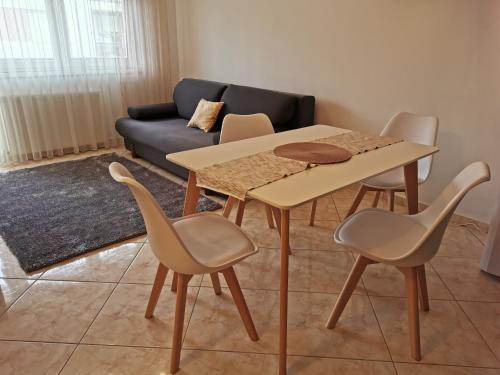 una mesa y sillas en una sala de estar con sofá en Noémi Wellness Apartman, en Siófok