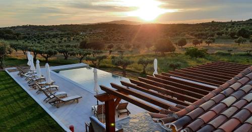 a view of a pool with chairs and the sunset at Quinta da Soneca in Alandroal