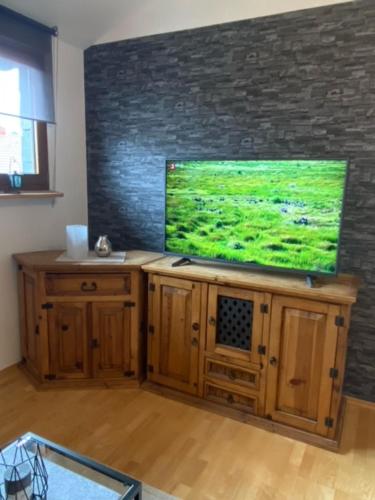 a living room with a flat screen tv on a wooden cabinet at Ferienwohnung am Panoramaweg in Mitlosheim