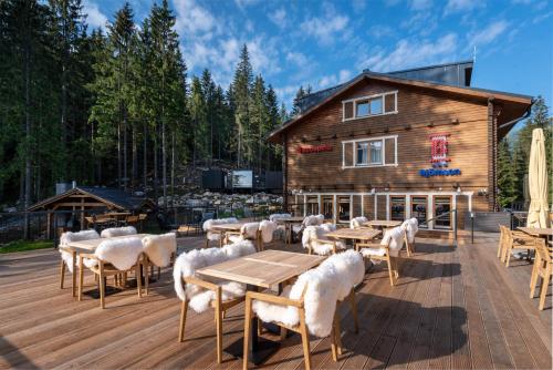 a wooden deck with tables and chairs and a building at Hotel Björnson & Björnson TREE HOUSES Jasná in Demanovska Dolina