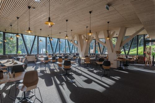 a large room with tables and chairs and windows at Hotel Björnson & Björnson TREE HOUSES Jasná in Demanovska Dolina