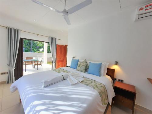 a bedroom with a large white bed with blue pillows at Palm Holiday Apartments in Grand'Anse Praslin