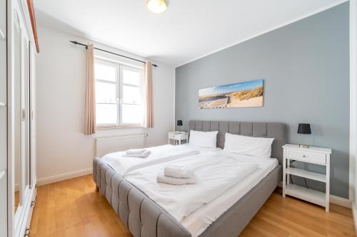 1 dormitorio con 1 cama grande con sábanas blancas en Residenz an der Prorer Wiek am Kurpark, en Binz