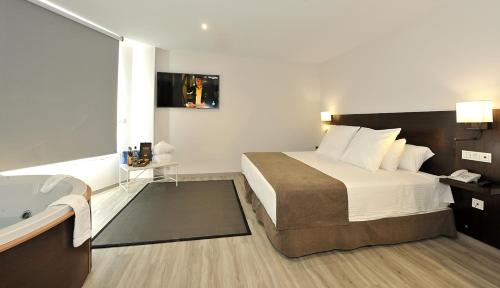 a hotel room with a bed and a bath tub at Hotel Salobreña Suites in Salobreña