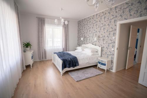 1 dormitorio con cama blanca y pared de color azul en Villa & Restoran Soffa, en Haapsalu